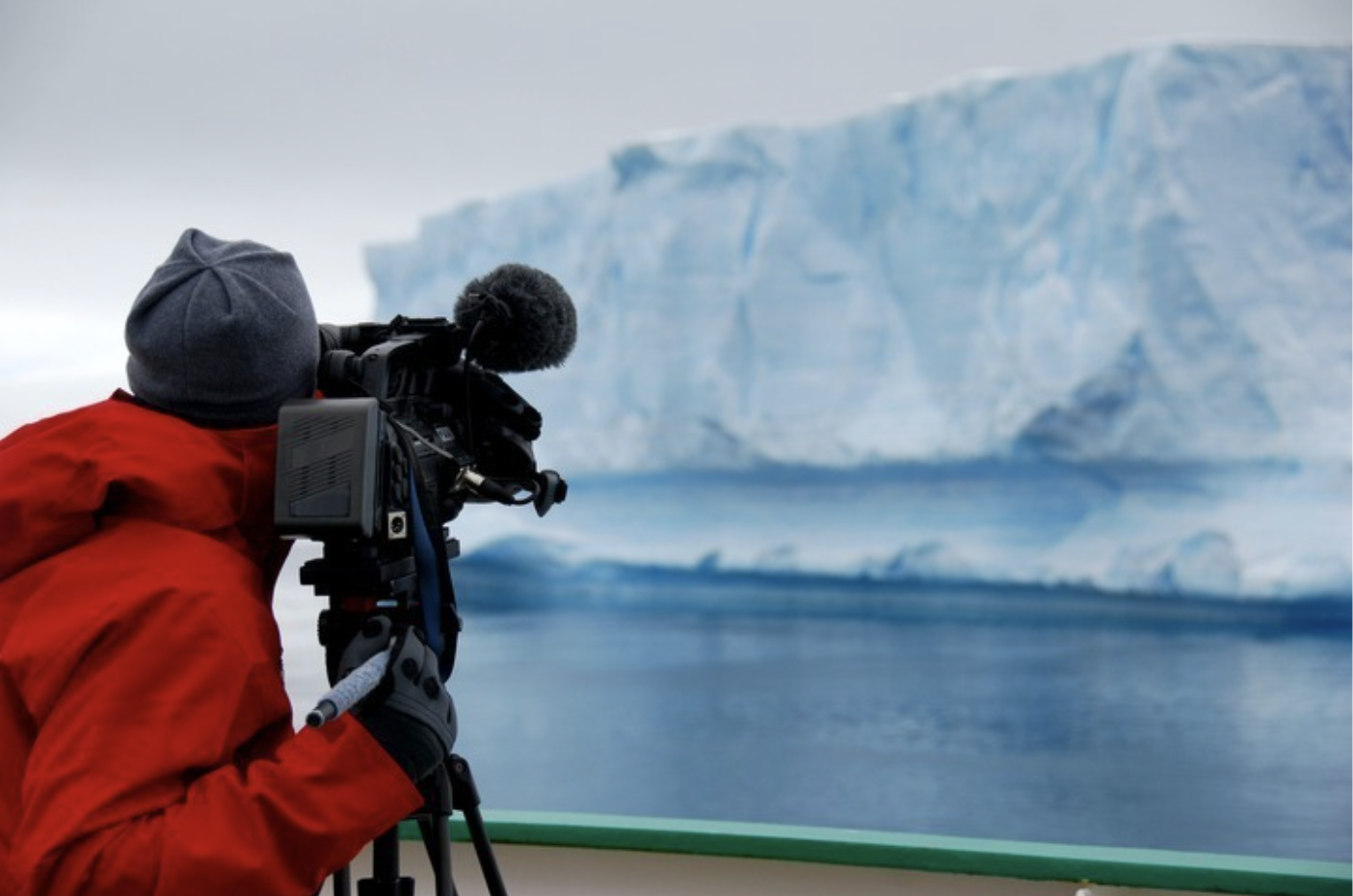 man photographing an iceberg